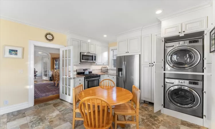 Kitchen featuring stacked washer / drying machine, white cabinetry, stainless steel appliances, and french doors