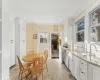 Kitchen with white cabinetry, sink, dishwasher, light stone counters, and crown molding