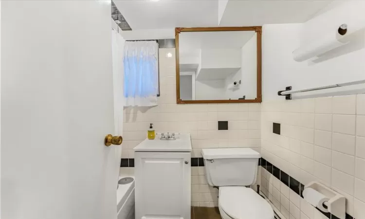 Bathroom featuring toilet, tile walls, and sink