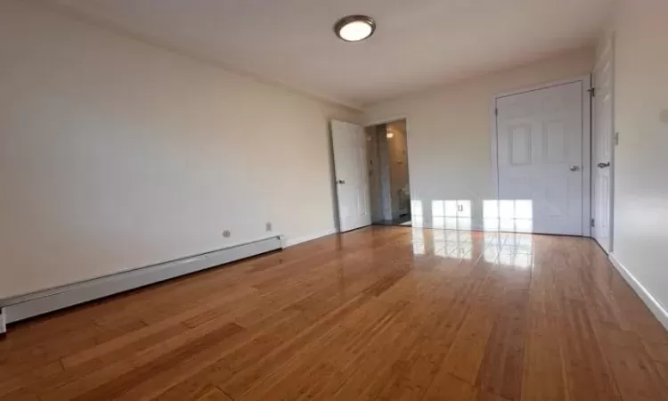 Empty room featuring light hardwood / wood-style flooring and a baseboard heating unit