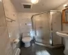 Bathroom featuring a baseboard radiator, an enclosed shower, tile walls, and toilet