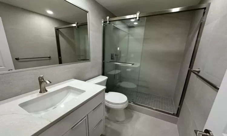 Bathroom featuring tile patterned floors, toilet, vanity, and walk in shower