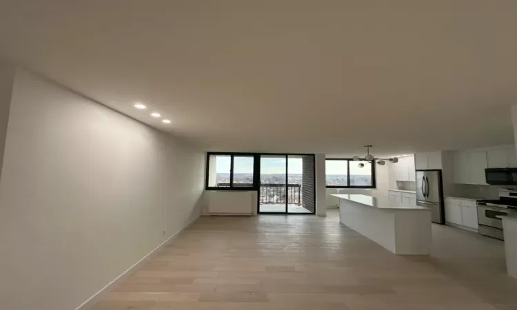 Kitchen featuring stainless steel fridge, stove, a center island, light hardwood / wood-style floors, and white cabinetry