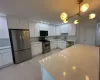 Kitchen featuring white cabinets, decorative light fixtures, sink, and stainless steel appliances