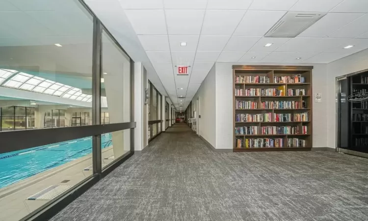 Hallway with a drop ceiling and dark colored carpet