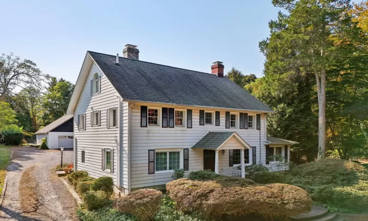 Colonial-style house featuring a garage and an outbuilding