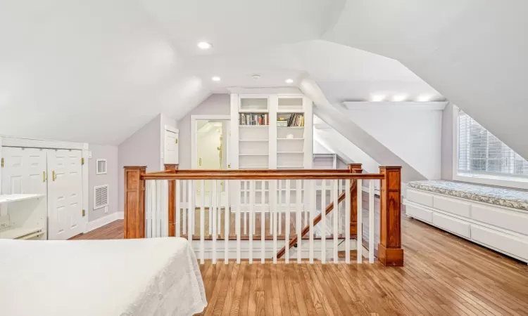 Bedroom featuring hardwood / wood-style floors, a baseboard radiator, and lofted ceiling