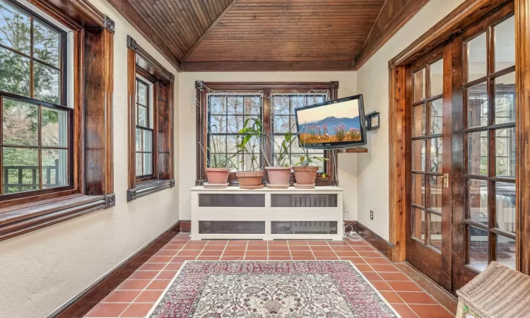 Entryway with plenty of natural light, wood ceiling, light tile patterned floors, and lofted ceiling with skylight