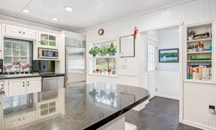 Kitchen featuring backsplash, white cabinets, sink, built in appliances, and kitchen peninsula