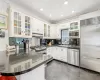 Kitchen featuring a breakfast bar area, built in appliances, kitchen peninsula, and white cabinets