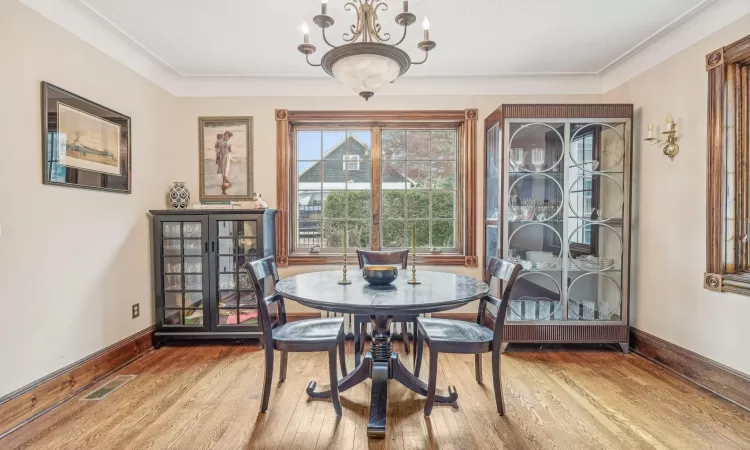 Dining area with hardwood / wood-style floors, an inviting chandelier, and crown molding