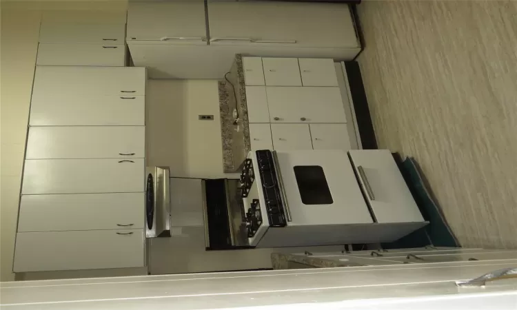 Kitchen featuring exhaust hood, white cabinets, refrigerator, stone countertops, and white range with gas stovetop