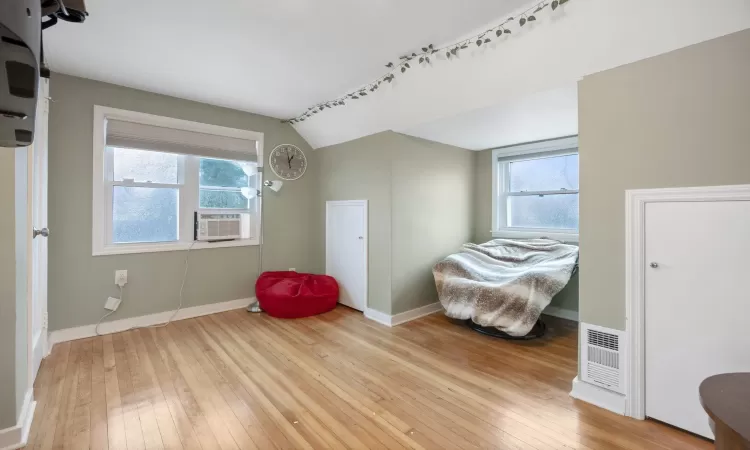 Sitting room featuring cooling unit, lofted ceiling, and light wood-type flooring