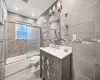 Full bathroom featuring bath / shower combo with glass door, vanity, crown molding, tile walls, and toilet