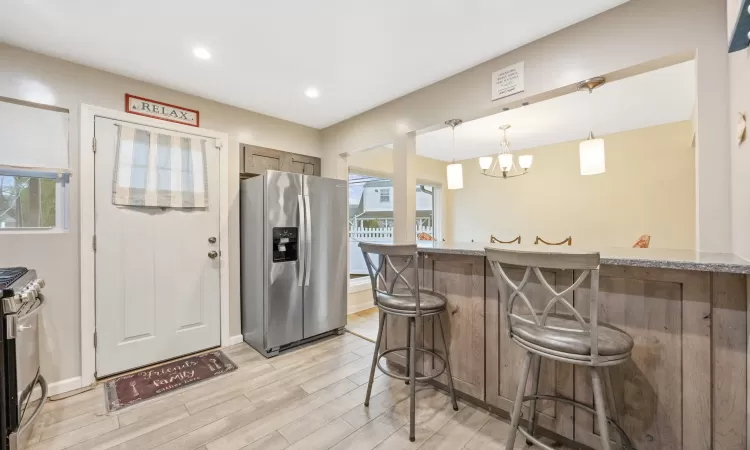 Kitchen featuring a healthy amount of sunlight, a kitchen bar, light wood-type flooring, and stainless steel appliances