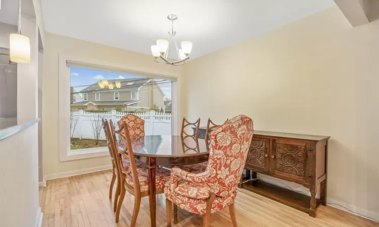 Dining room with light wood-type flooring, plenty of natural light, and a notable chandelier