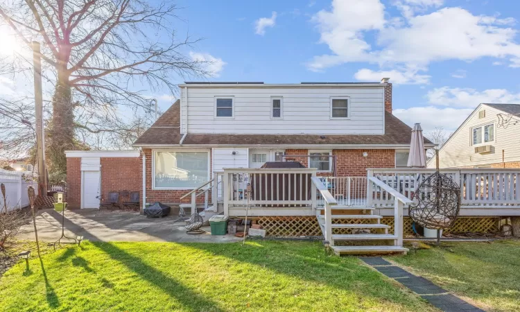 Back of house featuring a lawn and a deck