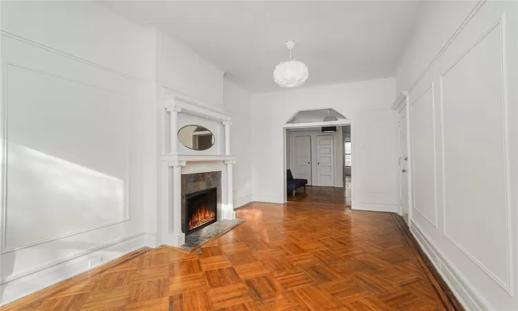 Unfurnished living room with parquet floors and a tiled fireplace