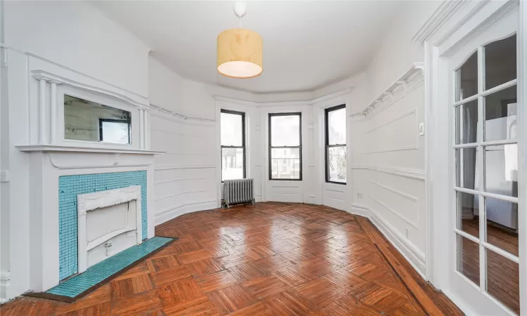 Unfurnished living room with dark parquet floors and radiator heating unit