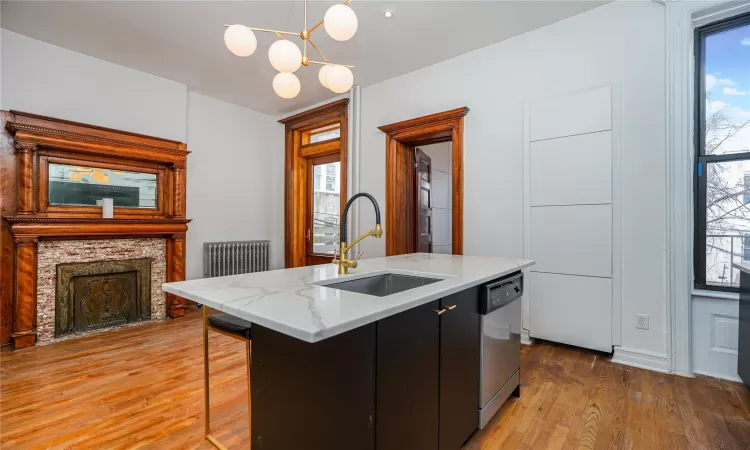 Kitchen featuring a kitchen island with sink, sink, hanging light fixtures, stainless steel dishwasher, and a healthy amount of sunlight