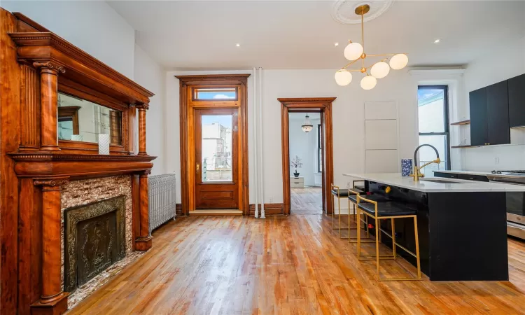 Kitchen featuring pendant lighting, a breakfast bar, stainless steel gas range oven, sink, and radiator heating unit