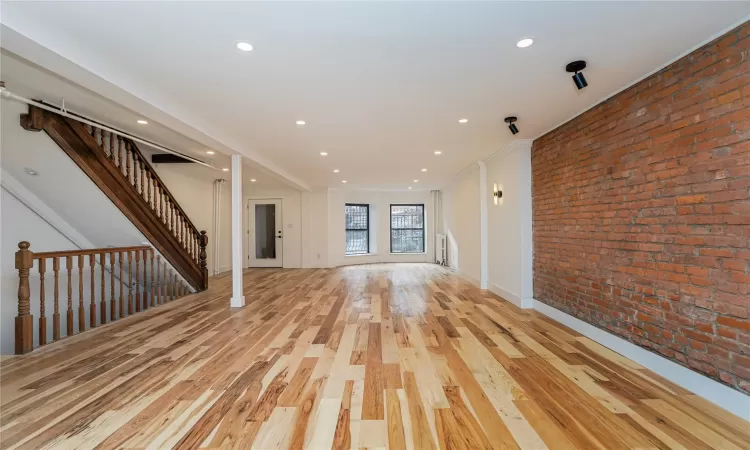 Unfurnished living room with light hardwood / wood-style flooring and brick wall