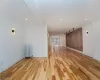 Empty room featuring light wood-type flooring, radiator, ornamental molding, and brick wall