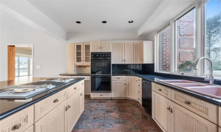 Kitchen with black appliances, decorative backsplash, sink, and light brown cabinetry