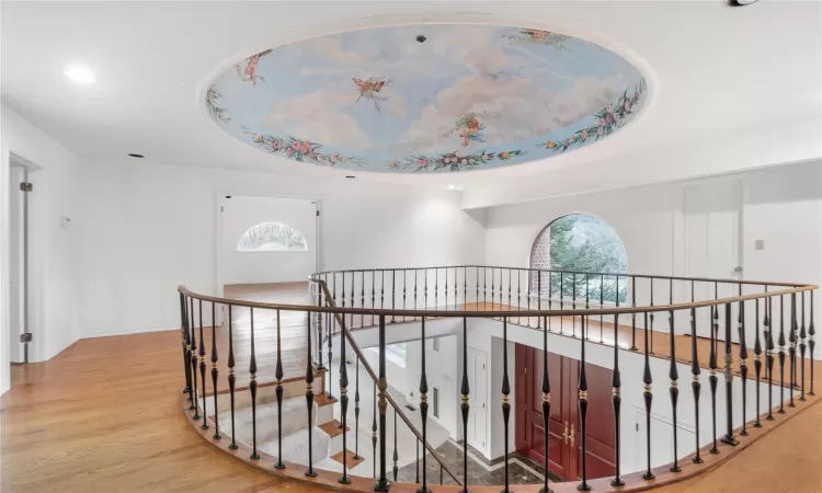 Hallway with a tray ceiling, plenty of natural light, and light hardwood / wood-style floors