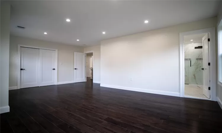 Unfurnished bedroom with dark hardwood / wood-style floors, connected bathroom, and a closet