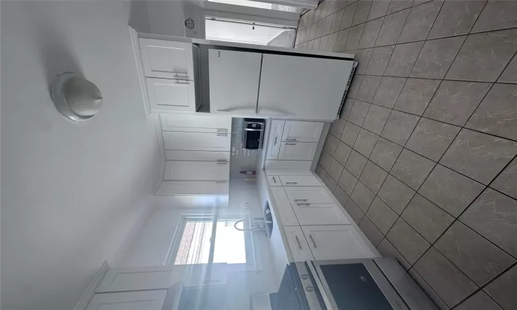 Kitchen featuring white cabinets, fridge, and sink