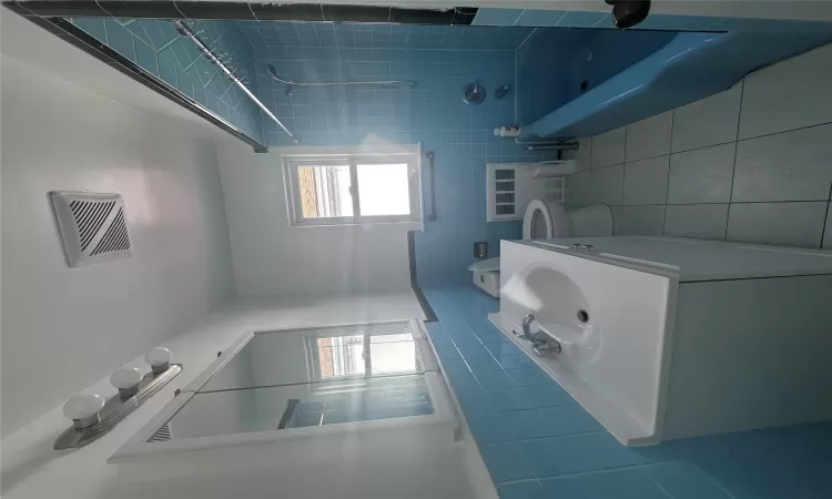 Full bathroom featuring vanity, tiled shower / bath, tile patterned flooring, tile walls, and radiator heating unit