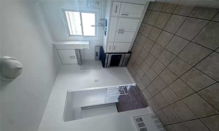 Kitchen with decorative backsplash, sink, exhaust hood, stainless steel stove, and white cabinetry