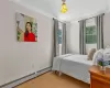 Bedroom featuring a baseboard radiator, ornamental molding, wood-type flooring, and multiple windows