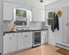 Kitchen with beverage cooler, light hardwood / wood-style floors, sink, and tasteful backsplash