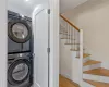 Laundry area featuring ornamental molding, stacked washer and dryer, and light wood-type flooring