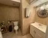 Bathroom featuring tile patterned flooring, vanity, tile walls, and toilet