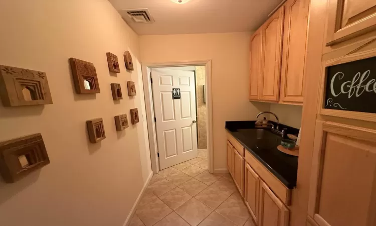 Kitchen with sink, light tile patterned flooring, and light brown cabinets