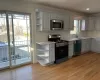 Kitchen featuring tasteful backsplash, stainless steel appliances, sink, light hardwood / wood-style flooring, and white cabinets