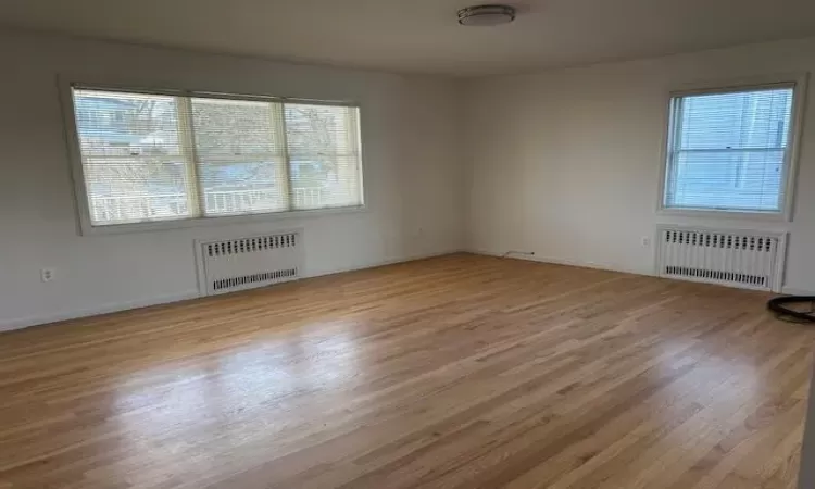 Empty room with radiator heating unit and light hardwood / wood-style floors