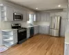 Kitchen with gray cabinetry, backsplash, sink, appliances with stainless steel finishes, and light hardwood / wood-style floors