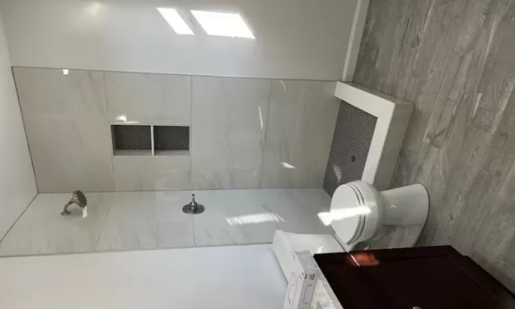 Bathroom with a tile shower, hardwood / wood-style flooring, vanity, and toilet