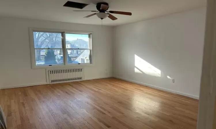 Spare room featuring ceiling fan, light hardwood / wood-style floors, and radiator heating unit