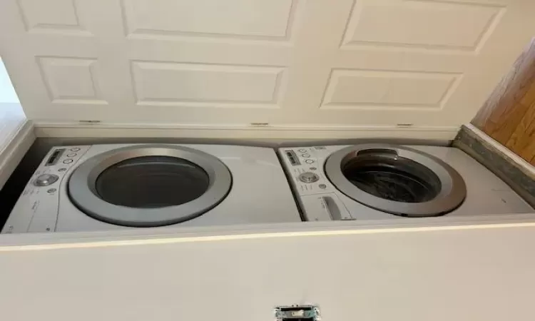 Laundry area featuring stacked washer and dryer and light hardwood / wood-style floors