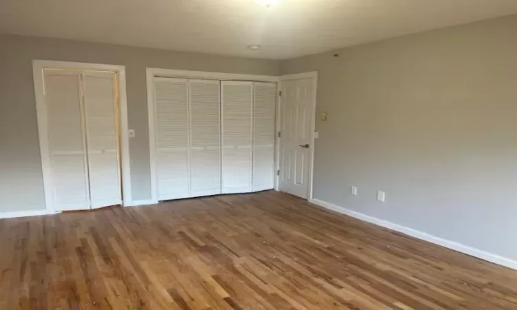 Unfurnished bedroom with two closets and hardwood / wood-style flooring