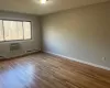 Primary bedroom with baseboard heating, a wall mounted AC, and hardwood flooring