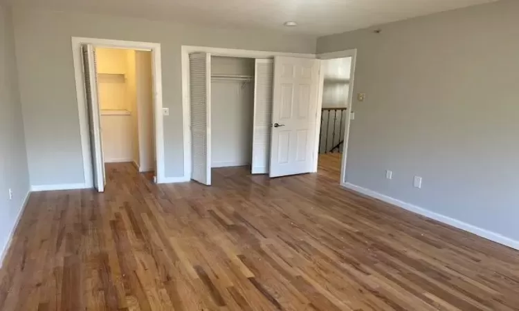 Unfurnished bedroom featuring dark hardwood / wood-style floors and a closet