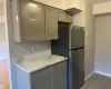 Kitchen featuring gray cabinetry, stainless steel fridge, hardwood / wood-style floors, and light stone counters