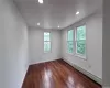 Empty room with dark wood-type flooring and a baseboard heating unit