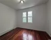 Unfurnished room featuring dark wood-type flooring and a baseboard heating unit